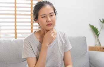 young woman with sore throat sitting on couch