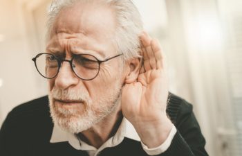 An elderly man with hearing problems trying to hear the sounds around